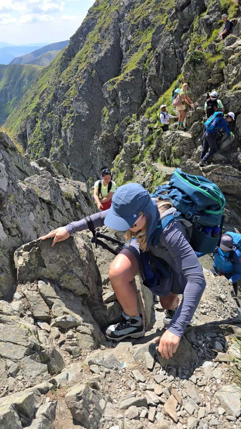 Alpinisti și drumeți pe traseu montan în Carpați, pe stânci abrupte.