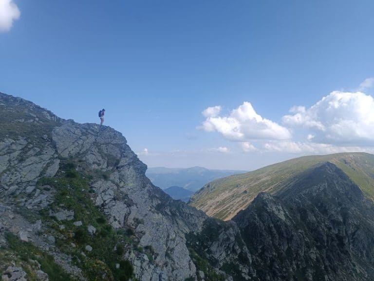 Persoană pe vârful munților Carpați, priveliște panoramică.