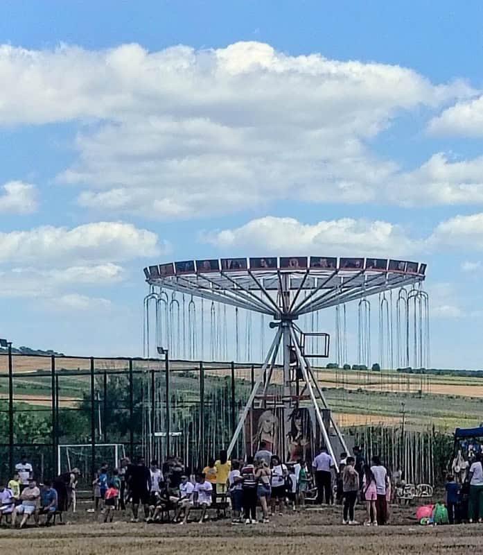 Târg de distracție cu carusel și oameni la evenimentul local.