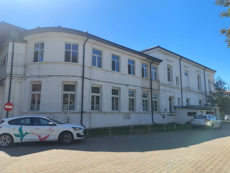 Clădire veche din Târgu Neamț cu ferestre mari și fațadă albă.
