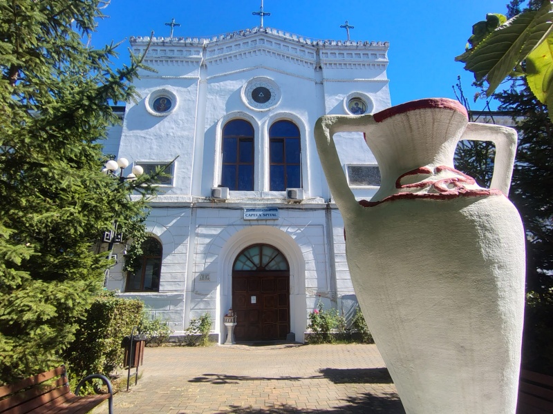 Biserica veche din Târgu Neamț cu un vas mare de lut în față.