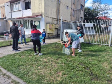 Mesaj de război la Târgu-Neamț: „Faceți rezerve”, spune primarul. Omenii întreabă furioși: „De unde, dacă nu avem apă?” Oamenii primesc apă dintr-un recipient în fața blocului.