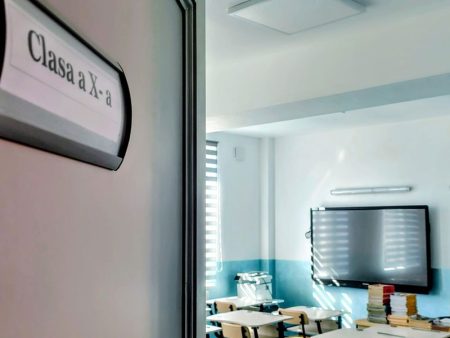 Sala de clasă modernă pentru elevi cu tablă digitală și mobilier.