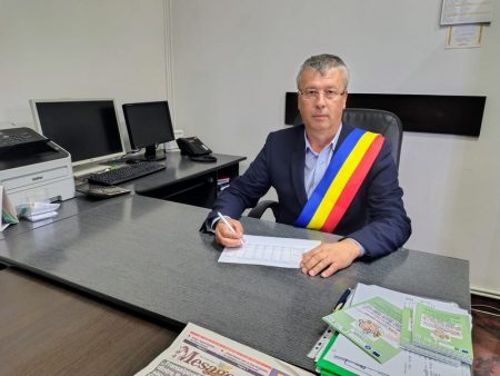 Oficial în birou, purtând eșarfă tricoloră, discută despre soluții financiare.