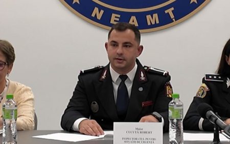Ofițer la masa conferință, birouri și logo NEAMȚ în fundal.