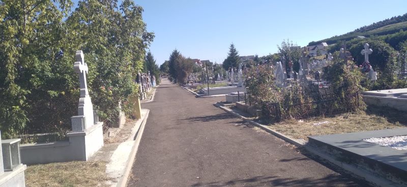 Cimitir cu alei pavate si cruci la marginea traseului.