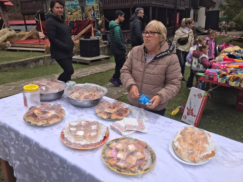 Femeie vânzând plăcinte și dulciuri la un targ cu mestesuguri.