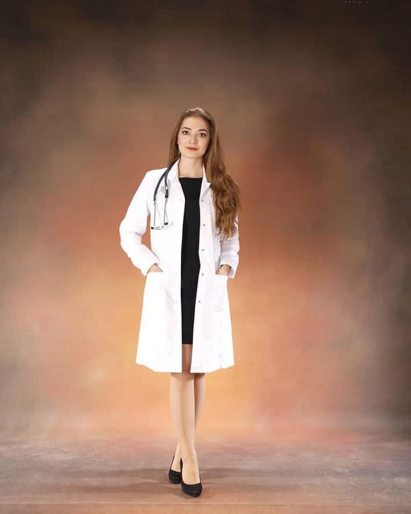 Medicul oncolog Alexandra Cumpănici în halat alb, cu stetoscop, într-un studio foto.