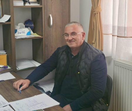 Bărbat zâmbitor în birou, pregătit pentru proiecte locale.