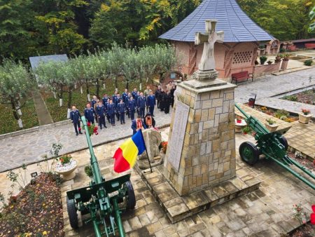 Grup de persoane lângă monument cu drapelul țării și un dispozitiv militar în fața mănăstă.