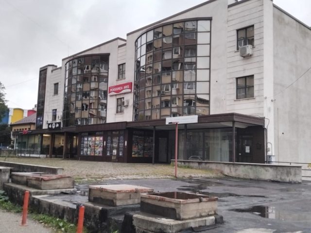 FOTO. Primăria Piatra-Neamț joacă din nou pe piața imobiliară: cumpără de la RIFIL un sediu și o parcare cu peste 1,1 milioane de euro Fațadă de clădire cu ferestre arcuite și vitrine, teren în față.
