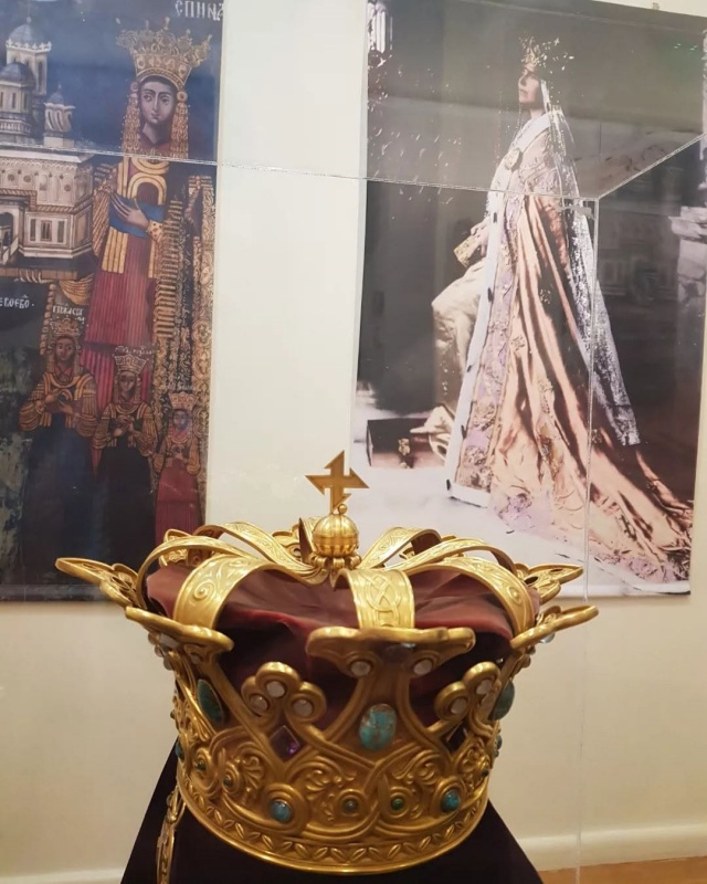 Coroană regală decorată cu pietre, expusă într-un muzeu.