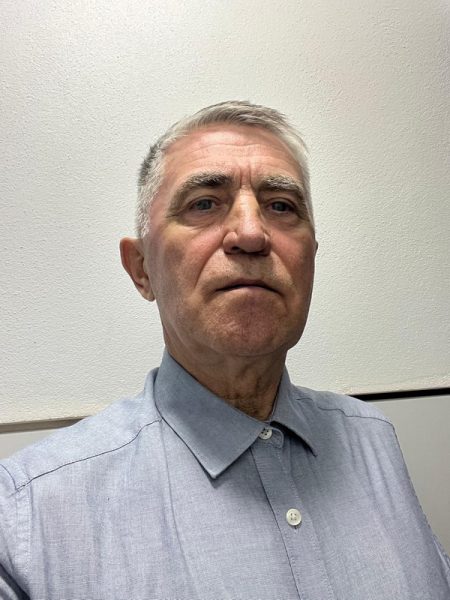 Portret al unui bărbat în cămașă albastră pe fundal neutr.